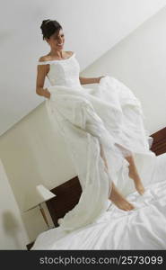 Low angle view of a bride jumping on the bed