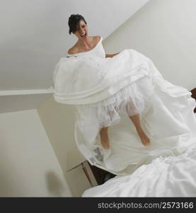 Low angle view of a bride jumping on the bed