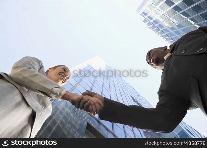 Low angle view of a businessman and a businesswoman shaking hands