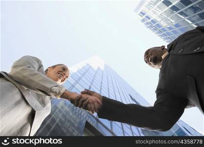 Low angle view of a businessman and a businesswoman shaking hands