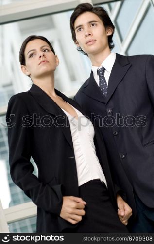 Low angle view of a businessman and a businesswoman standing together in front of a window