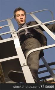 Low angle view of a businessman climbing up a ladder