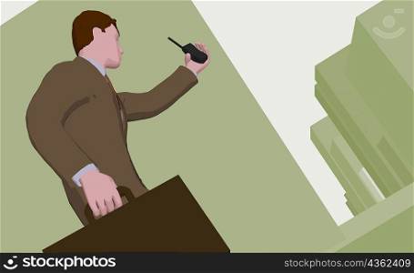 Low angle view of a businessman holding a briefcase and a cordless phone
