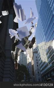 Low angle view of a businessman jumping and throwing papers