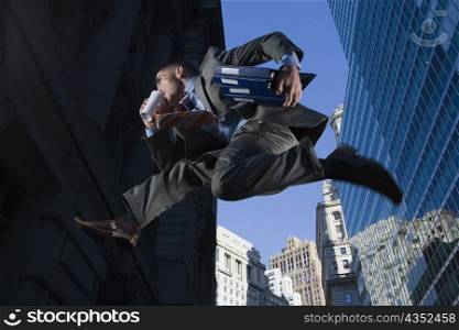 Low angle view of a businessman jumping in mid-air and drinking