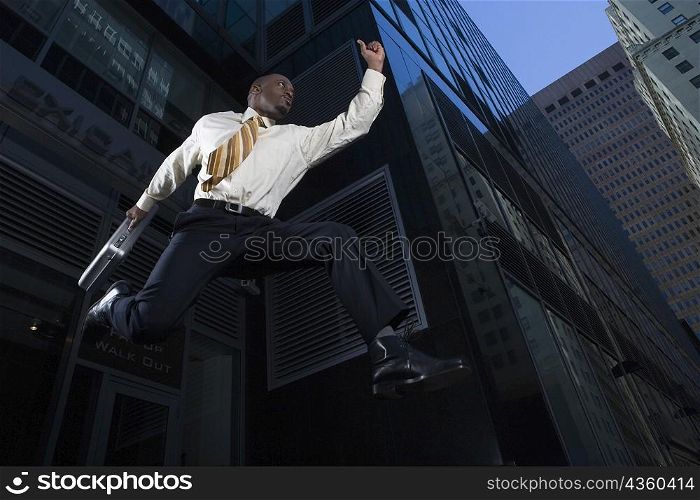 Low angle view of a businessman jumping with a briefcase