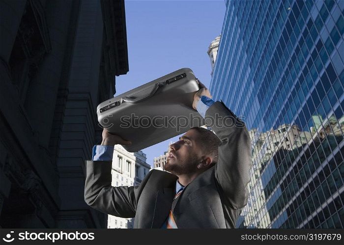 Low angle view of a businessman protecting himself with a briefcase