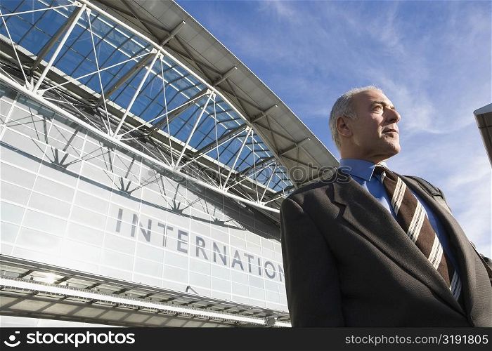 Low angle view of a businessman standing outside an airport building