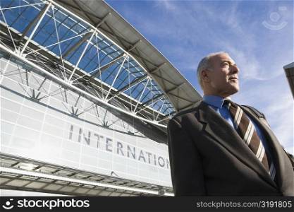 Low angle view of a businessman standing outside an airport building