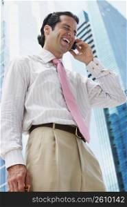Low angle view of a businessman talking on a mobile phone and laughing