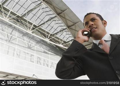 Low angle view of a businessman talking on a mobile phone outside an airport