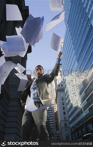 Low angle view of a businessman throwing sheet of papers in air