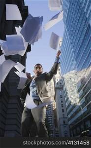 Low angle view of a businessman throwing sheet of papers in air