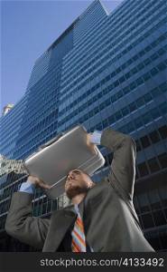Low angle view of a businessman using his briefcase as a shade