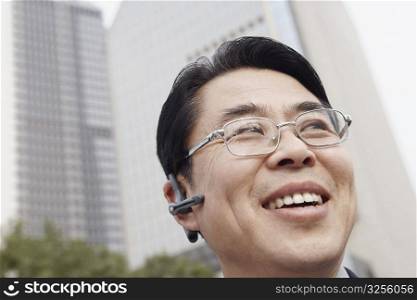 Low angle view of a businessman wearing a hands free device smiling