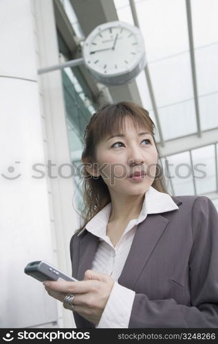 Low angle view of a businesswoman holding a mobile phone and waiting at an airport lounge