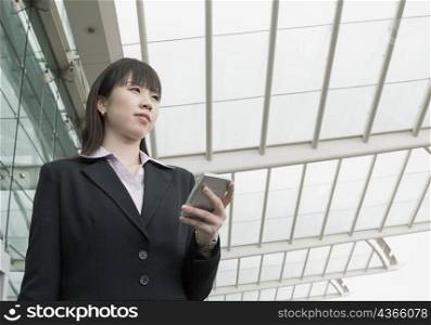 Low angle view of a businesswoman holding a personal data assistant and waiting at an airport lounge