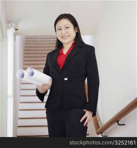Low angle view of a businesswoman holding rolled up charts and smiling