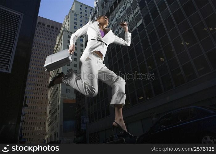 Low angle view of a businesswoman jumping with a briefcase