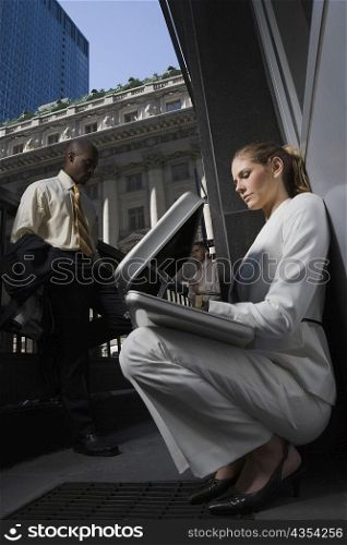 Low angle view of a businesswoman looking into a briefcase with two businessmen standing in the background