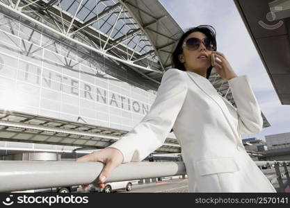 Low angle view of a businesswoman talking on a mobile phone outside an airport