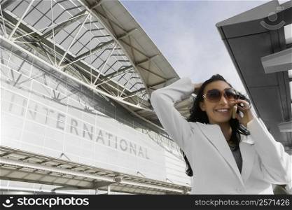 Low angle view of a businesswoman talking on a mobile phone outside an airport