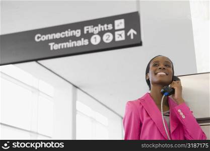 Low angle view of a businesswoman talking on a pay phone at an airport