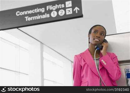 Low angle view of a businesswoman talking on a pay phone at an airport