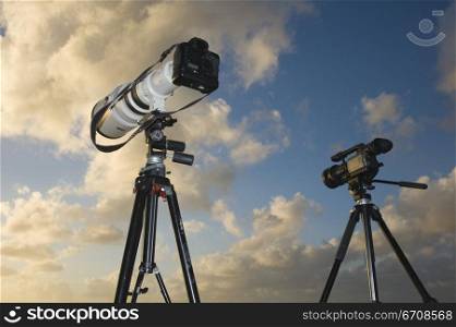 Low angle view of a camera and a video camera on tripods