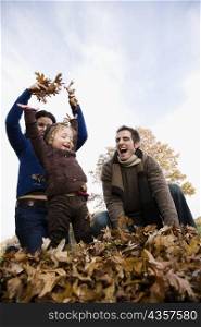Low angle view of a couple and their daughter playing with leaves