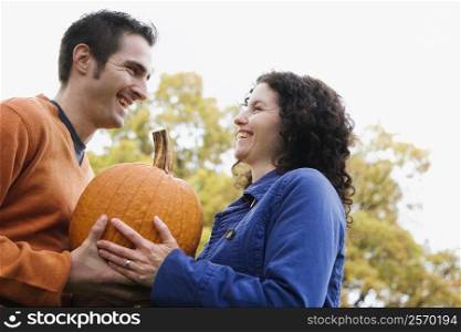 Low angle view of a couple sharing a pumpkin and smiling