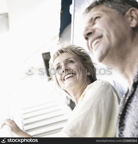 Low angle view of a couple standing on the staircase of a cruise ship and smiling