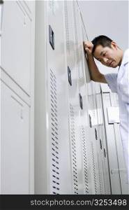 Low angle view of a doctor leaning against a locker