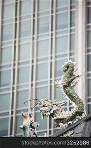 Low angle view of a dragon sculpture in a temple with a building in the background