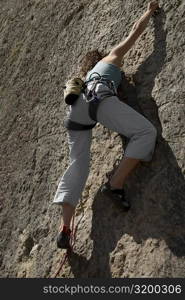 Low angle view of a female rock climber scaling a rock face