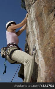 Low angle view of a female rock climber scaling a rock face