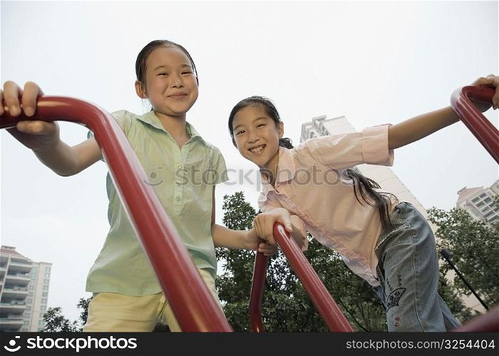 Low angle view of a girl and her sister playing on a merry-go-round