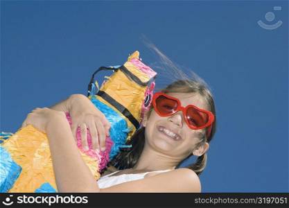 Low angle view of a girl holding a rocking horse and smiling