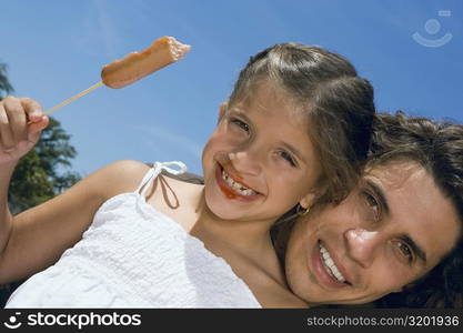 Low angle view of a girl holding a sausage with her father