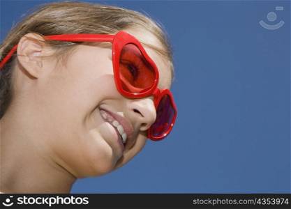 Low angle view of a girl wearing red sunglasses and smiling