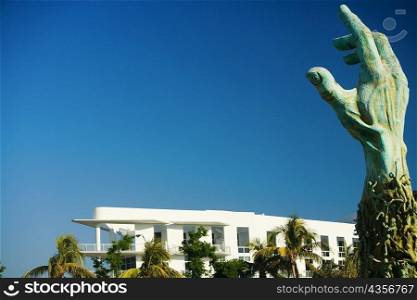 Low angle view of a hand sculpture near a building
