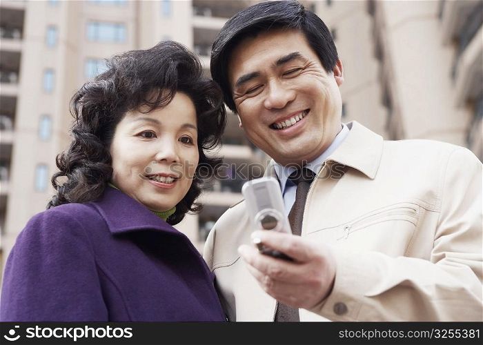 Low angle view of a mature couple looking at a mobile phone smiling