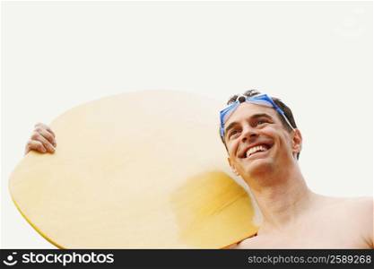 Low angle view of a mature man carrying a surfboard and smiling