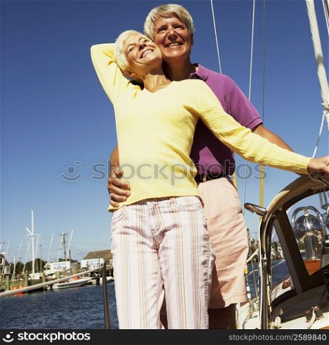 Low angle view of a mature man embracing a mature woman from behind in a boat and smiling