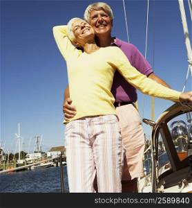 Low angle view of a mature man embracing a mature woman from behind in a boat and smiling