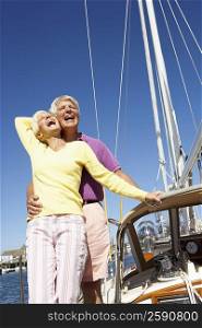 Low angle view of a mature man embracing a mature woman from behind in a boat and laughing
