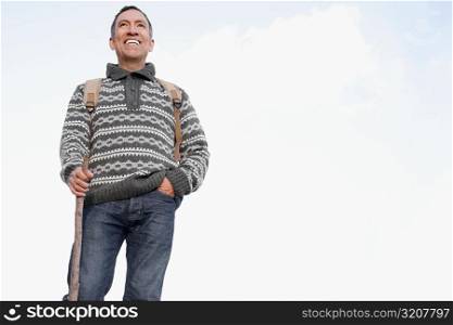 Low angle view of a mature man holding a hiking pole and smiling