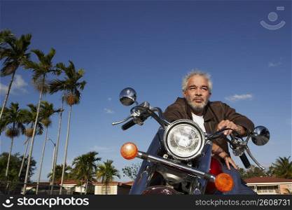 Low angle view of a mature man sitting on a motorcycle