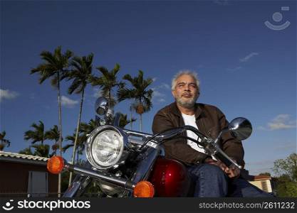 Low angle view of a mature man sitting on a motorcycle
