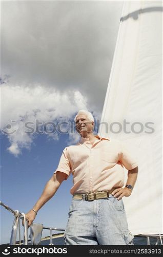 Low angle view of a mature man standing in a sailboat and smiling